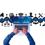 A man's hands and forearms typing on a laptop viewed from above